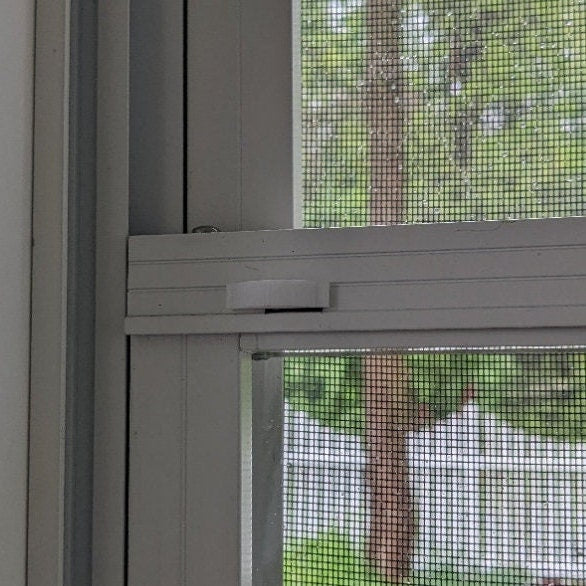 White thumb latch attached in window frame